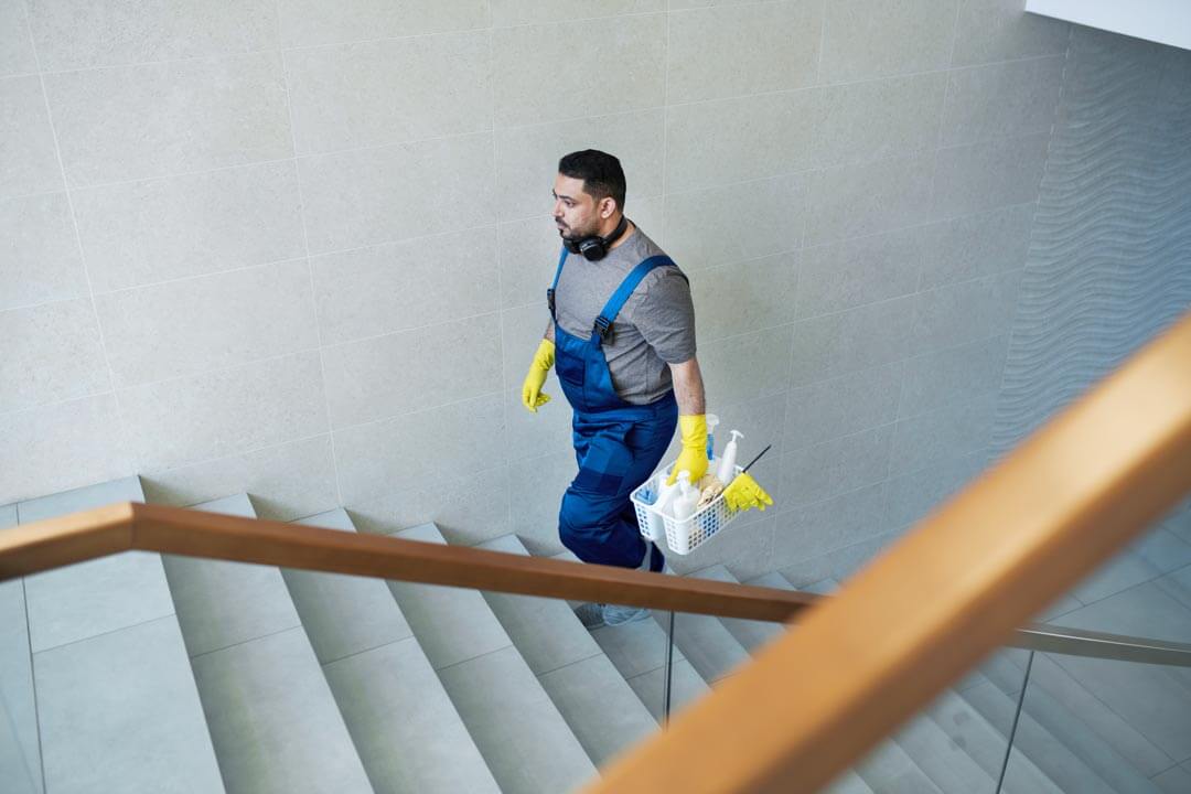 Pulizie condominiale Milano: uomo delle pulizie sale le scale con secchio prodotti